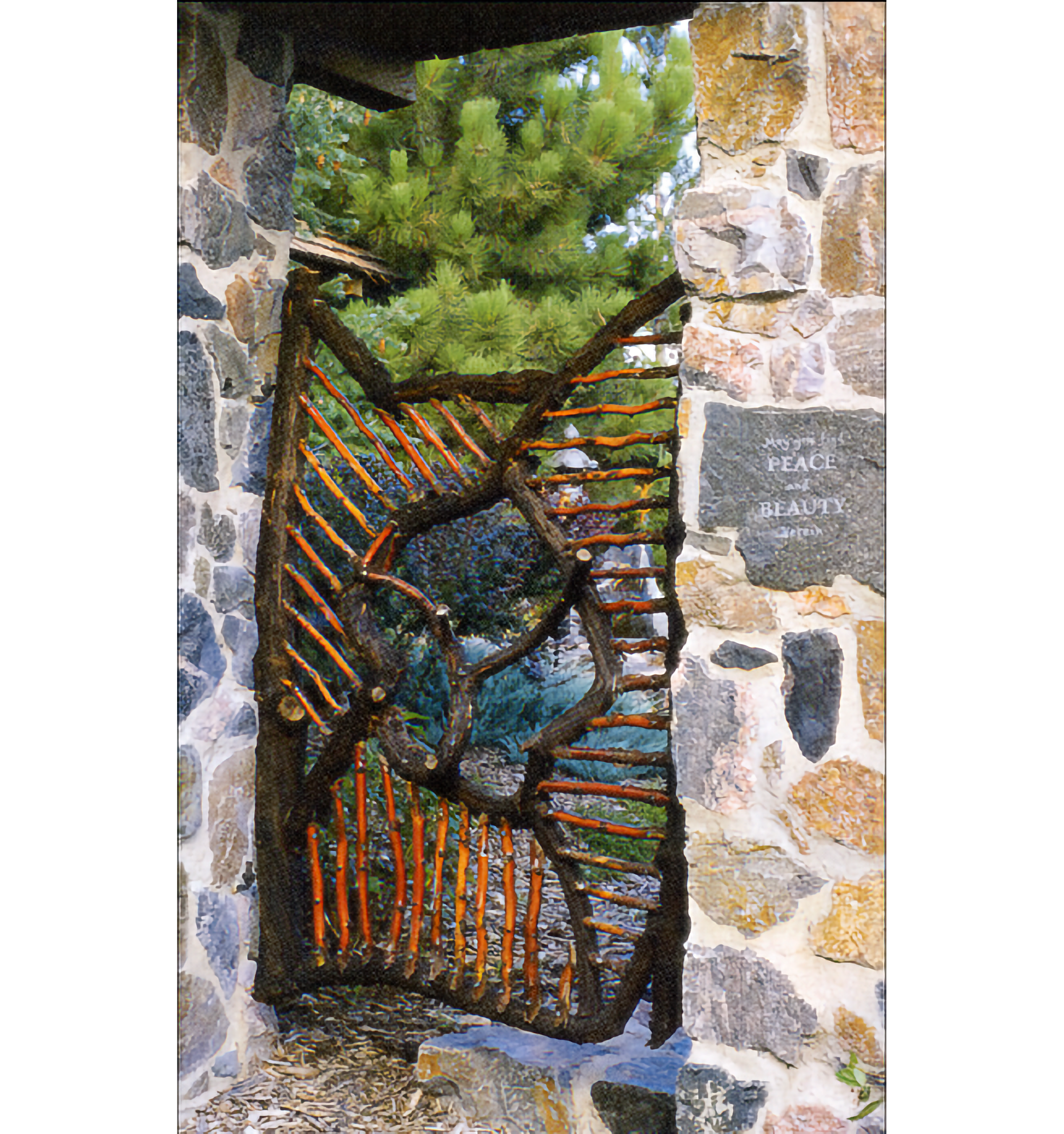 Photo of stone-sided entrance to garden, with a gate made of dark and light brown branches