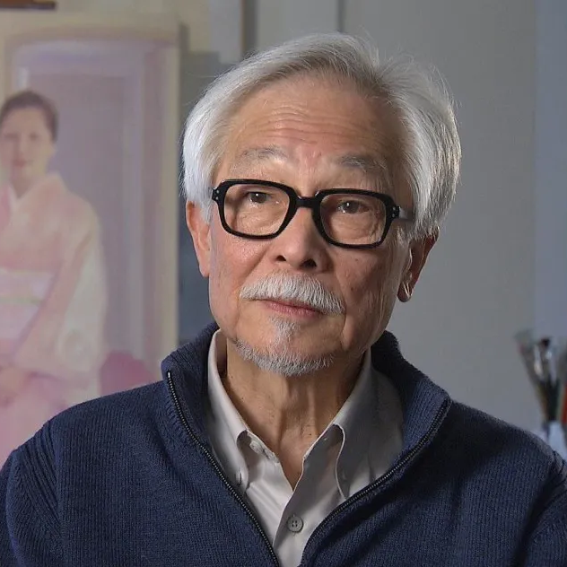 Photo of artist Allen Say looking slightly to his right, wearing a blue sip jacket and with black glasses