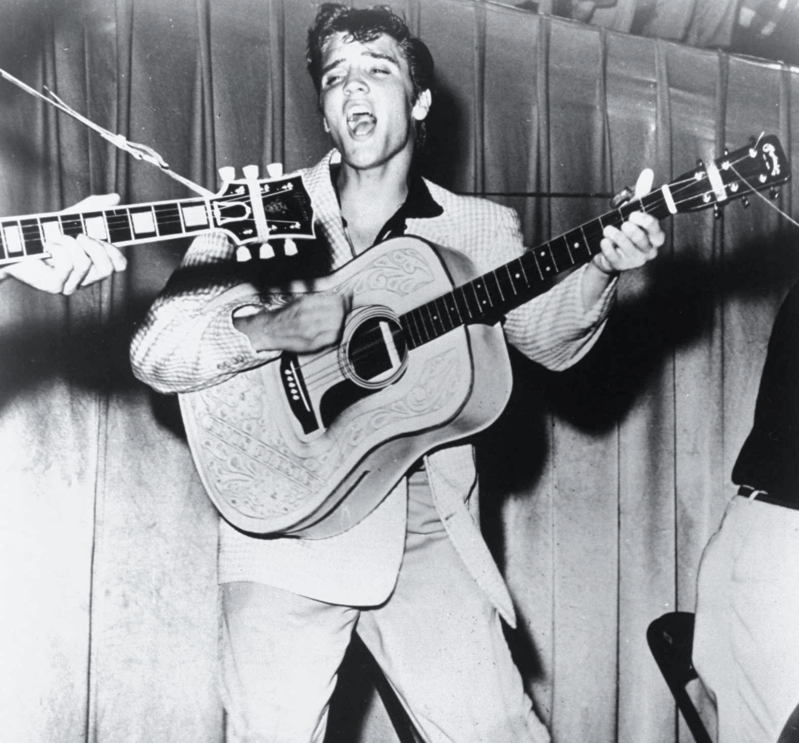 Photo of Elvis singing while playing a guitar