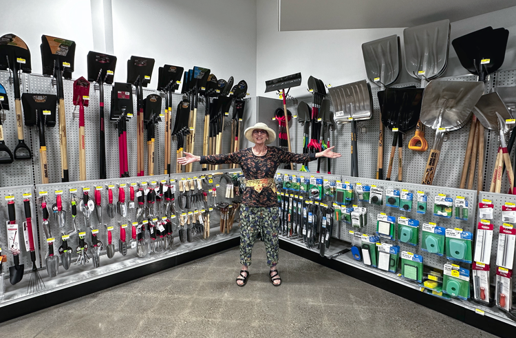 Photo of Sandra Dean in middle of display of shovels, trowels, pruners, and other garden tools and supplies