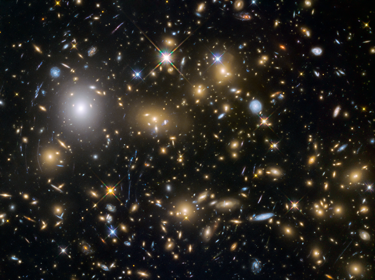 Photo of multiple star galaxies, brown and blue, against black sky.