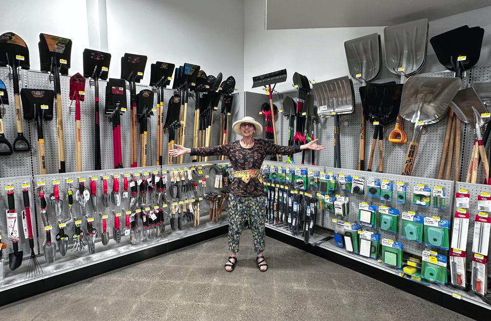 Photo of Sandra Dean in middle of display of shovels, trowels, pruners, and other garden tools and supplies